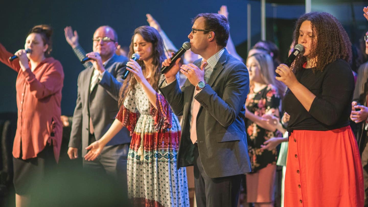 Sänger performen leidenschaftlich in Mikrofone auf einer Bühne.